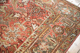 Distressed hand-knotted Heriz rug with geometric palmettes, tomato red and celadon green tones.