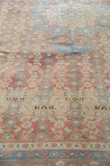 Low pile distressed vintage Bijar carpet with repeating Herati motifs in red, blue, and beige.