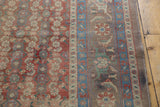 Distressed Bijar rug showing brick red Herati field and brown border with stylized animals.