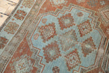 Distressed Afshar rug corner, detailed geometric guls in sky blue, brick red, and etched charcoal.