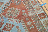 Distressed vintage rug section, featuring a stepped sky blue motif and brick red field.