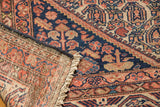 Vintage Malayer rug corner, showing intricate blue-red patterns, its woven foundation, and secured fringe.