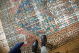 Textured pile and distressed areas of a vintage Malayer runner in denim blue, brick red.