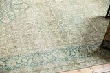 Distressed vintage Tabriz carpet corner, showcasing faded Herati motifs and wide teal border.
