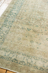 Distressed vintage Tabriz carpet showing worn pile with faded teal, ivory, and brown patterns.