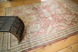 Decorative distressed corner of a Mahal rug, showcasing raspberry floral leaves and ivory palmettes.