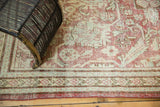 Distressed vintage Persian Mahal rug close-up: worn raspberry red, sea foam green floral patterns.