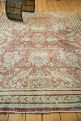 Faded raspberry and ivory floral patterns with distressed texture on a vintage Mahal carpet.