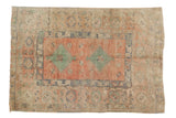 Distressed Turkish Oushak rug with faded brick red field, emerald green medallions, and wide blue border.