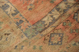 Abrashed texture of a distressed vintage Oushak rug in faded brick red, blue, and sand.