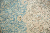 Close-up of distressed Sivas carpet's blue and beige scrolling vinery, with foundation showing through.