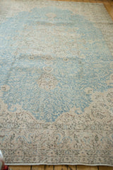 Distressed Sivas carpet corner showing faded blue, antique ivory, and scrolling vinery border.