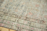Distressed Khotan rug texture revealing foundation, faded apricot and celadon tones, with reverse markings.