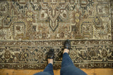 Distressed vintage Heriz carpet, geometric patterns, prominent turtle/samovar border, and rich brown-gray tones.