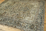 Distressed vintage Heriz carpet corner featuring geometric turtle/samovar border in earthy tones.