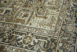 Distressed Heriz carpet detail with geometric motifs, 'turtle' border, and coffee brown tones.