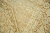 Distressed Afshar rug detail with scalloped contours, boteh motifs, in sand, brown, and seafoam.