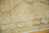 Distressed Afshar carpet detail with worn geometric patterns in sand, faded coffee brown, sea foam.