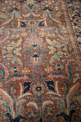 Detail of vintage Heriz carpet's expressive floral design in brick red, navy blue, and copper green hues.