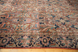 Navy blue patterned border and worn brick red floral field of a vintage Heriz carpet.