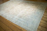 Distressed vintage Sparta carpet shows worn ivory field and pale blue curvilinear design.