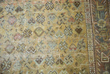 Close-up of distressed Afshar rug, geometric motifs in muted rose, sage, and blue.