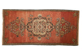 Vintage Oushak rug runner with a Rococo floral medallion on an abrashed brick red field.