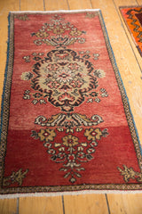 Vintage Oushak rug corner, abrashed brick red field, stylized floral motif, and blue border.