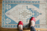 Distressed vintage Oushak rug with teal, ivory, beige geometric medallion and intact selvage.