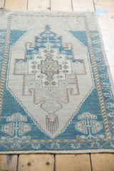 Vintage distressed Oushak rug's lower border, teal germinating plant motifs, low pile.