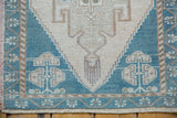 Distressed teal corner with geometric germinating plant motif and fringe on a vintage Oushak rug.