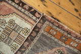 Distressed Oushak rug corner showing low pile, burnt orange, and chocolate geometric motifs.