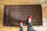 Geometric pattern detail of vintage Belouch rug; brown, navy, and rose colors, secure fringe.