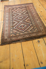 Vintage Belouch rug corner with dark chocolate fringe, geometric border, and dusty rose tones.