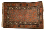 Vintage Belouch rug with central geometric medallions and distinct crab border in earthy tones.