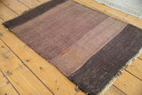 Hand woven Turkish Kilim rug corner, with charcoal-eggplant striated band and fringed end.