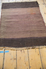 Close-up of the secured, woven fringe and dark eggplant band on the vintage Turkish Kilim rug.