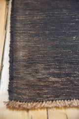 Dark charcoal vintage Turkish Kilim rug showing wefted texture with abrashes and secured edge.