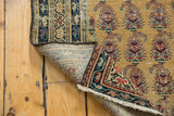 Folded vintage Malayer rug reveals hand-knotted foundation, saffron field, and paisley motifs.