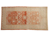 Distressed vintage Khotan rug runner with a cherry red field, beige shadow medallions, and soft floral motifs.