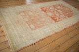 Angled view of a distressed Khotan runner showing cherry red abrashes and a soft seafoam border.