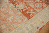 Detailed view of the distressed, low pile showing cherry red and seafoam floral motifs on a vintage Khotan rug.