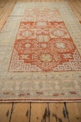 Angled perspective showing the low pile and floral motifs on a distressed vintage Khotan rug runner.