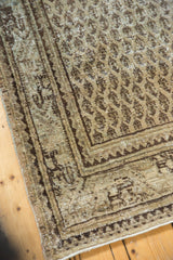Textured distressed Mir Serbend rug corner, beige and charcoal boteh motif visible.