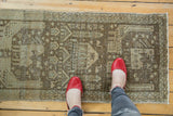 Distressed Sivas runner with pictorial village motifs, antique ivory, beige, and bronze tones, feet for scale.
