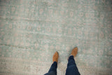 Distressed texture of a vintage Sparta carpet showing faded seafoam green floral vinery with ivory foundation.