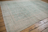 Textured edge of the distressed Sparta carpet, featuring faded seafoam green and ivory floral patterns.