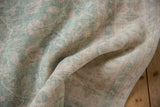 Folded vintage Distressed Sparta rug, highlighting worn texture, pale seafoam green, and floral vinery.