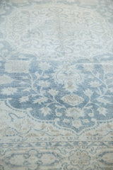 Pale teal and ivory Rococo stylized leaves on a distressed Oushak carpet.