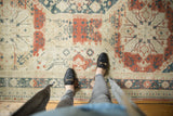 Distressed Sivas carpet's faded red, teal, and ivory floral and curvilinear pattern.